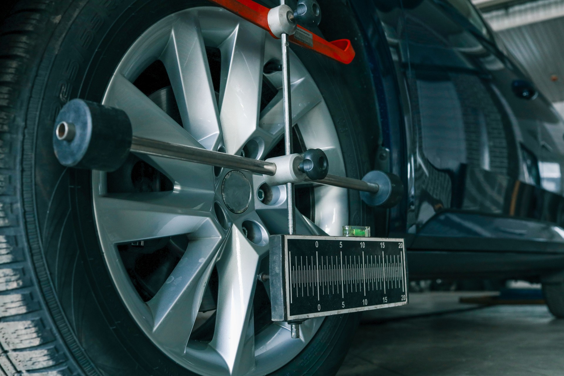 Close-up of a car wheel being measured for alignment using professional calibration equipment in an auto workshop